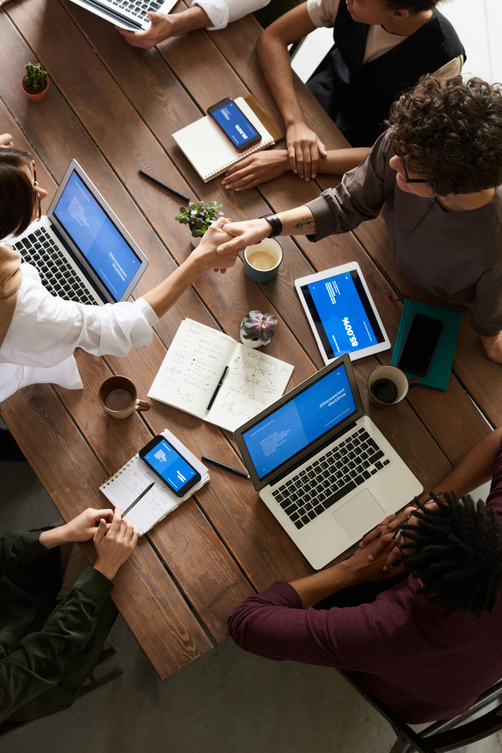 A diverse group of professionals brainstorming in a modern workspace with laptops and notebooks.